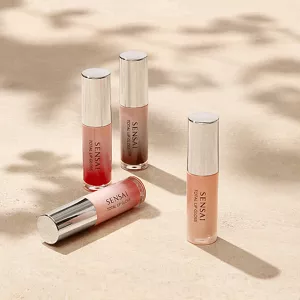 Total Lip Gloss in Colours accanto all'originale su una superficie neutra con illuminazione d'atmosfera